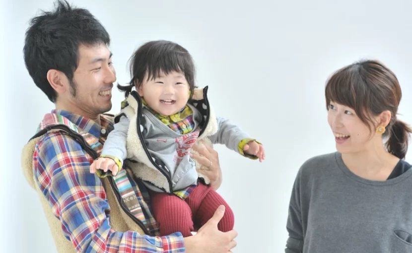 パパに抱っこされて笑顔の赤ちゃんと見つめるママ